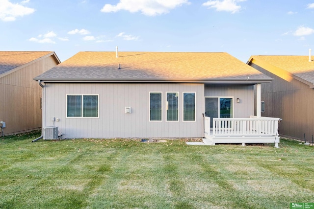 rear view of property featuring central air condition unit, a wooden deck, a shingled roof, and a yard