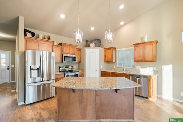 kitchen with stainless steel appliances, light wood-style floors, a sink, and a kitchen island