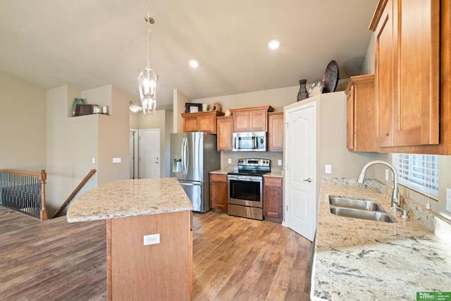 kitchen with light wood finished floors, appliances with stainless steel finishes, a sink, and a center island