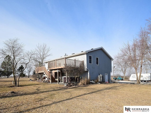 rear view of property with a yard, a deck, and stairs