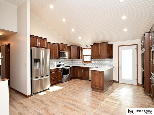 kitchen featuring light wood finished floors, stainless steel appliances, light countertops, backsplash, and high vaulted ceiling