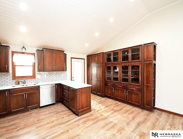 kitchen with lofted ceiling, a peninsula, a sink, light countertops, and dishwasher