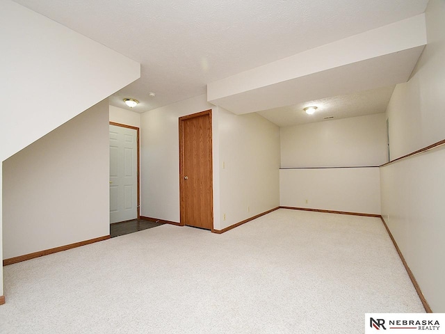 interior space featuring carpet flooring, a textured ceiling, and baseboards