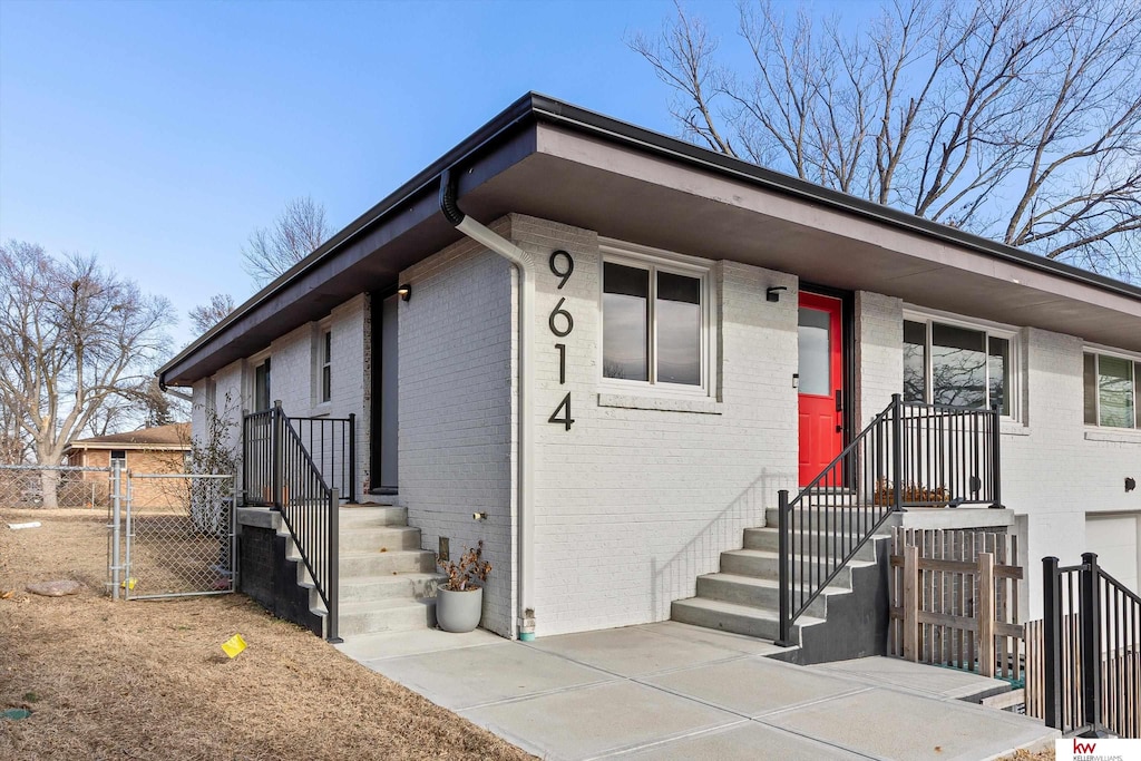 view of front of home featuring a gate, brick siding, and fence