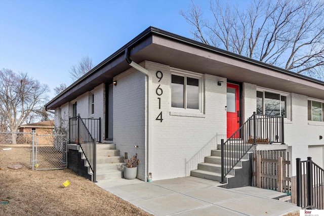 view of front of home featuring a gate, brick siding, and fence