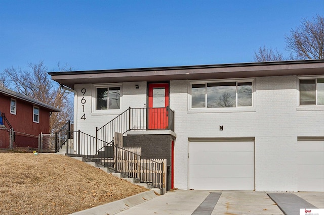 view of front of home featuring concrete driveway, brick siding, an attached garage, and fence