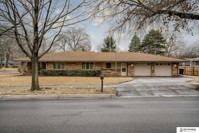 ranch-style home featuring concrete driveway, a chimney, an attached garage, and fence