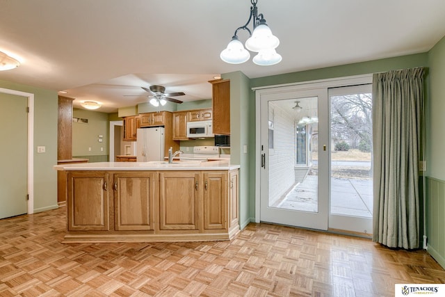 kitchen featuring light countertops, hanging light fixtures, visible vents, white appliances, and a peninsula