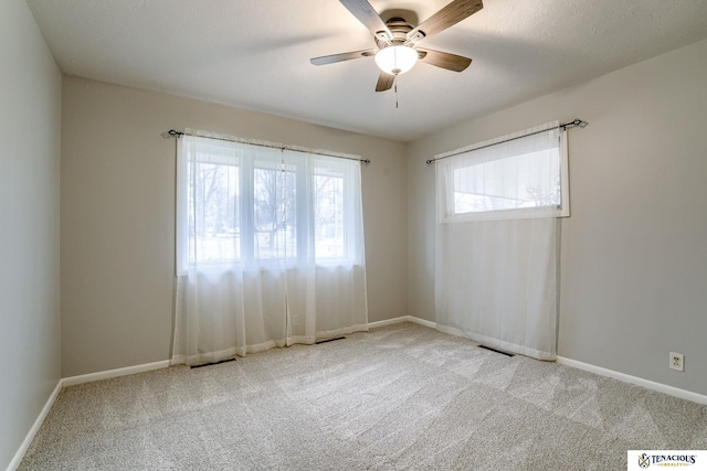 carpeted spare room featuring visible vents, ceiling fan, and baseboards