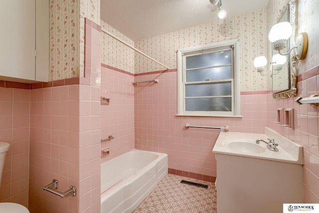 full bath with toilet, tile walls, shower / bathing tub combination, wainscoting, and wallpapered walls