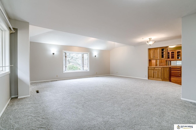 carpeted empty room featuring visible vents, baseboards, and vaulted ceiling