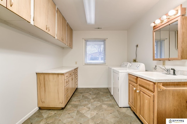 clothes washing area with cabinet space, baseboards, separate washer and dryer, and a sink