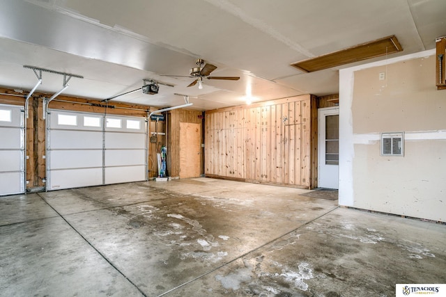 garage featuring wooden walls, visible vents, and a garage door opener