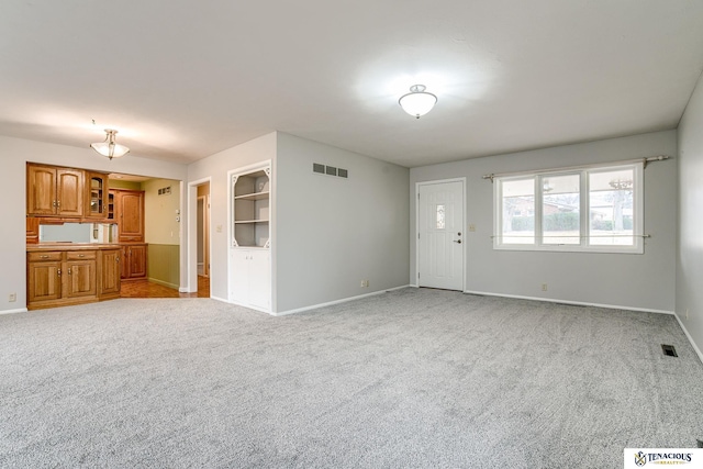 unfurnished living room featuring visible vents, light carpet, and baseboards