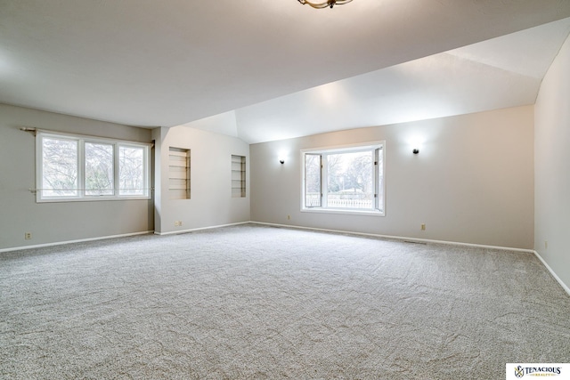 carpeted empty room featuring vaulted ceiling, visible vents, and baseboards