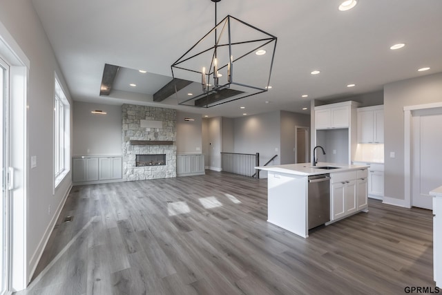 kitchen featuring white cabinetry, open floor plan, stainless steel dishwasher, and wood finished floors