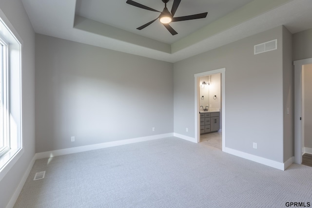 unfurnished bedroom featuring a raised ceiling, visible vents, and multiple windows