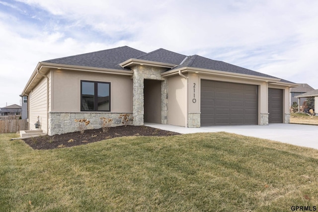 prairie-style home featuring stone siding, a shingled roof, a front yard, and driveway