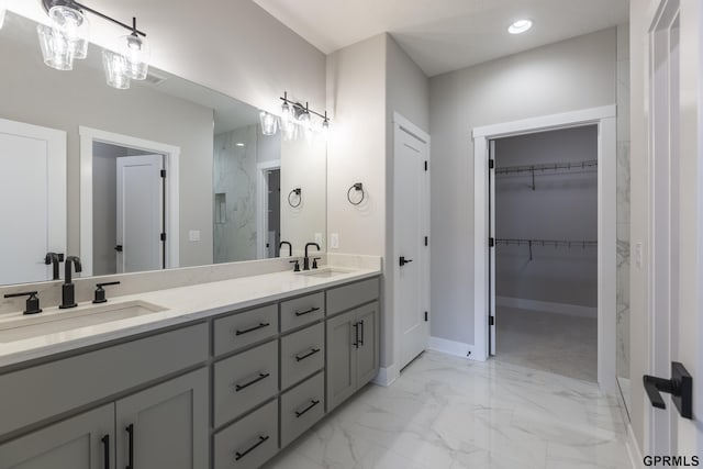 bathroom featuring marble finish floor, double vanity, a spacious closet, and a sink