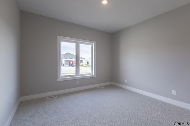 unfurnished room with carpet floors, visible vents, and baseboards