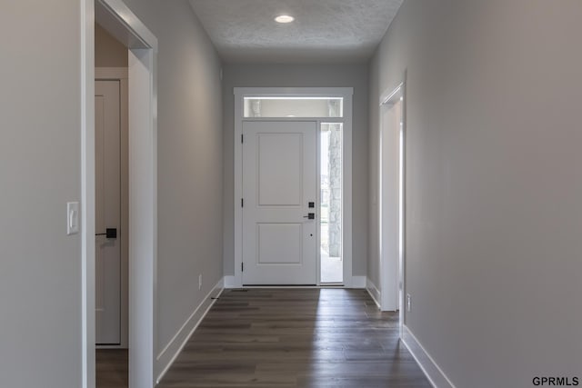 entrance foyer with a textured ceiling, dark wood finished floors, and baseboards