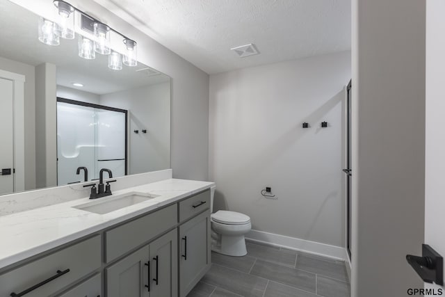 bathroom with a textured ceiling, toilet, visible vents, baseboards, and a shower stall