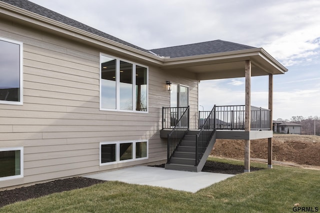 back of property featuring a deck, a yard, a shingled roof, and stairway