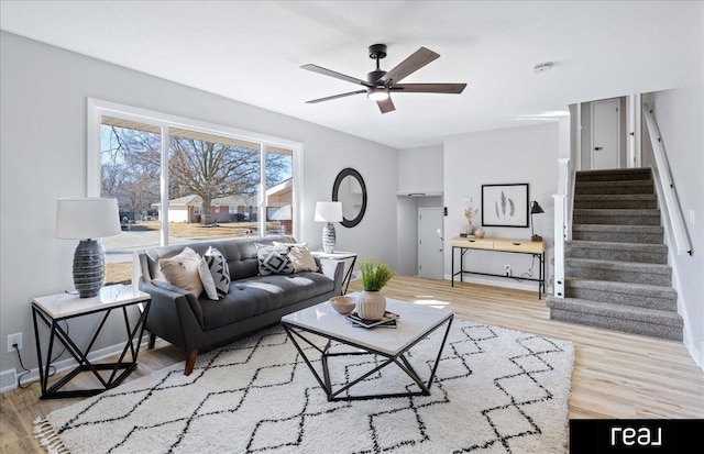 living room featuring stairway, wood finished floors, a ceiling fan, and baseboards