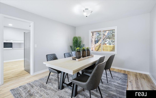 dining space featuring light wood-style floors and baseboards