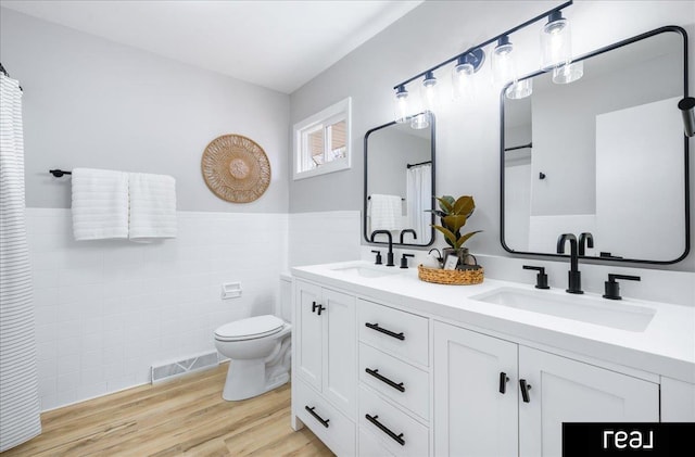 bathroom featuring toilet, wainscoting, a sink, and visible vents