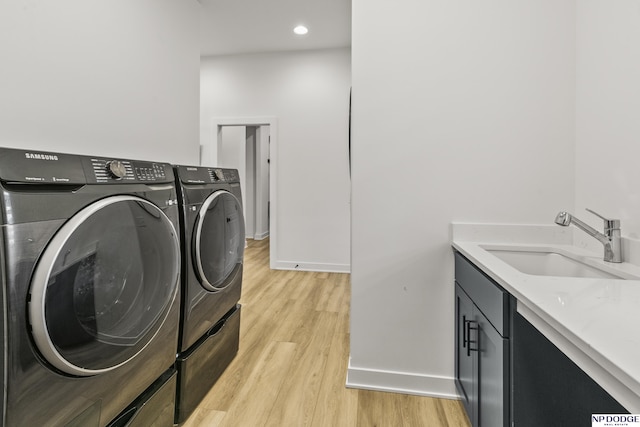 laundry area with cabinet space, baseboards, washer and dryer, light wood-style floors, and a sink