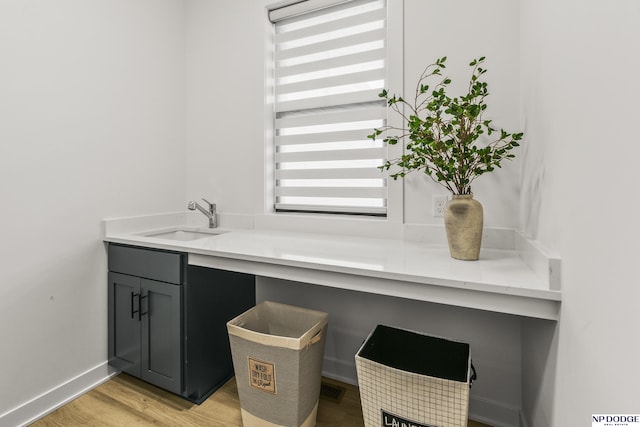 interior space featuring light wood-type flooring, a sink, visible vents, and baseboards