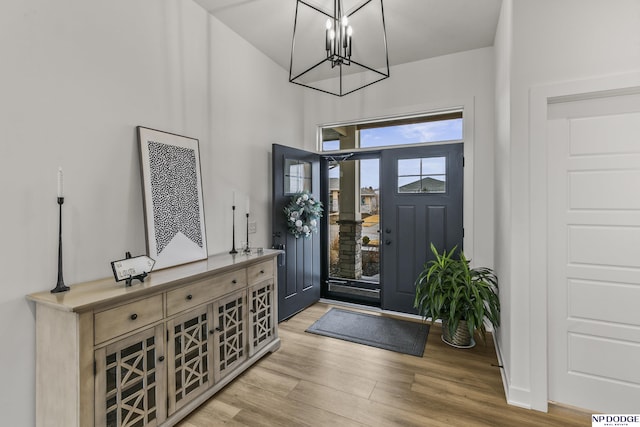 foyer with baseboards, an inviting chandelier, and wood finished floors