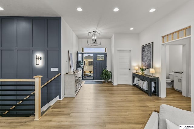 entrance foyer with a chandelier, light wood-style floors, recessed lighting, and a decorative wall