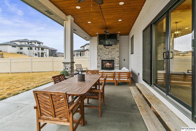 view of patio / terrace with outdoor dining area, fence, an outdoor living space with a fireplace, and ceiling fan