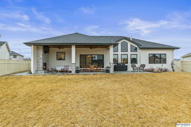 rear view of house with a yard, a shingled roof, a patio area, ceiling fan, and a fenced backyard