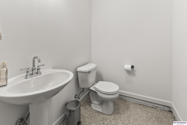 half bathroom featuring a sink, toilet, and baseboards