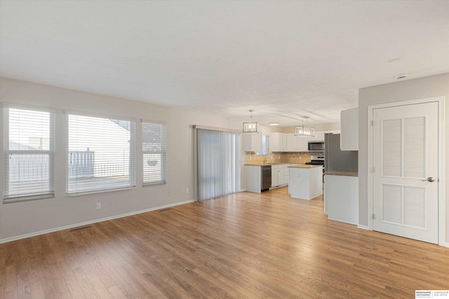 unfurnished living room with light wood-style flooring and baseboards