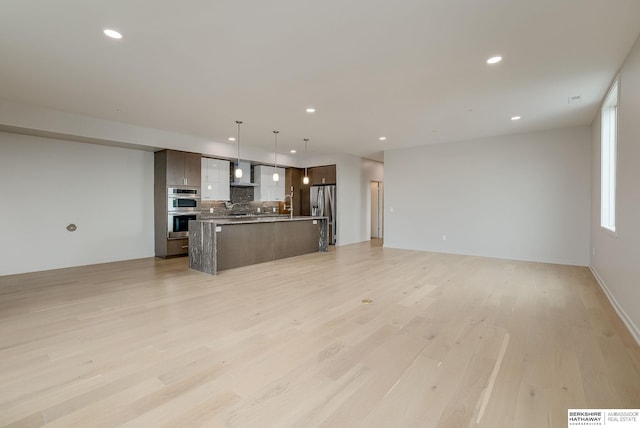 unfurnished living room featuring a sink, light wood-style flooring, and recessed lighting