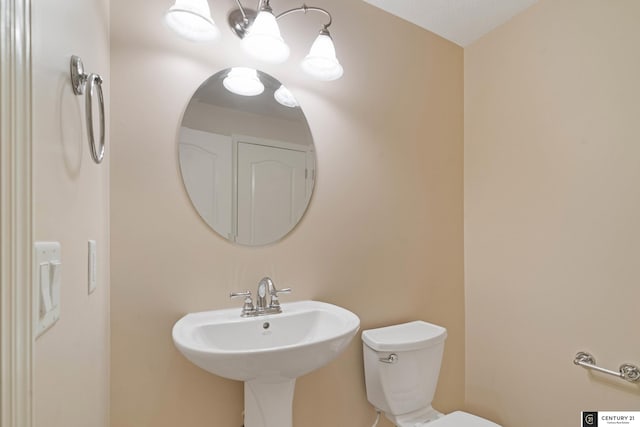 half bath with toilet, a chandelier, and a sink