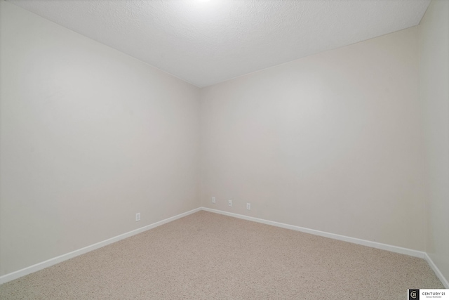 carpeted spare room with a textured ceiling and baseboards