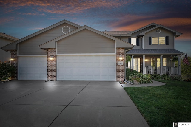 traditional-style home with concrete driveway, an attached garage, a yard, a porch, and brick siding