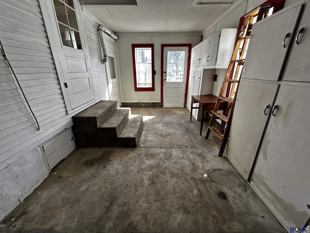 interior space featuring unfinished concrete floors and white cabinets