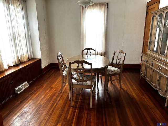 dining room with dark wood-style floors, visible vents, and baseboards