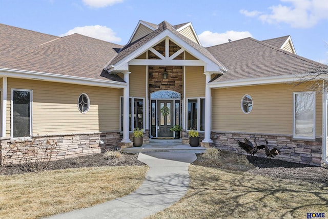 view of front of house with stone siding and roof with shingles