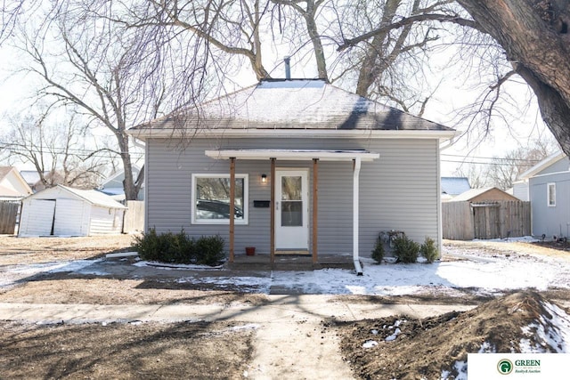 bungalow-style home featuring covered porch, roof with shingles, and fence