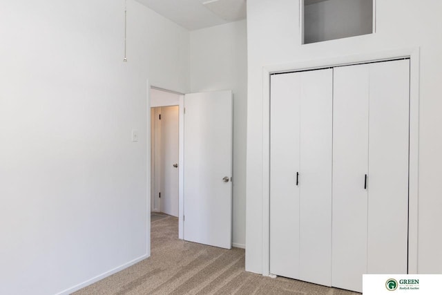 unfurnished bedroom featuring baseboards, a closet, and light colored carpet