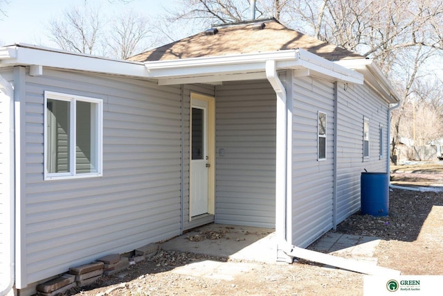 doorway to property with a shingled roof