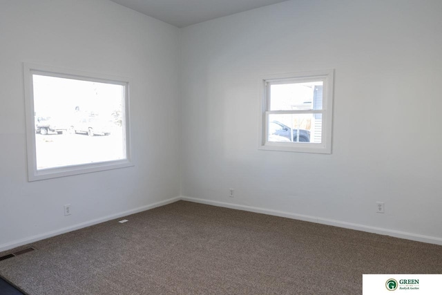 empty room with carpet, visible vents, and baseboards