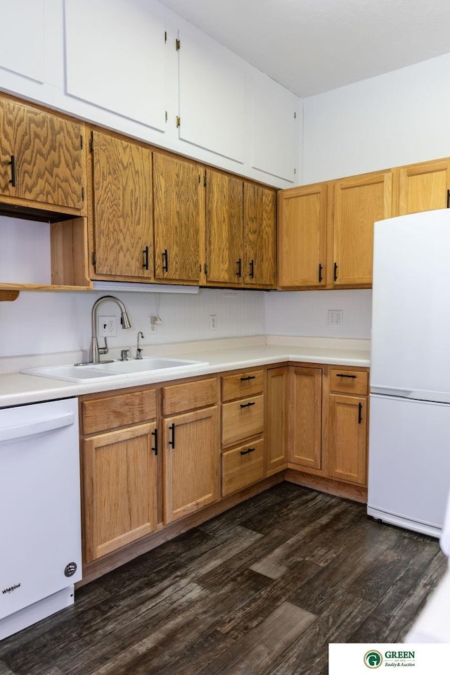 kitchen with a sink, white appliances, dark wood finished floors, and light countertops